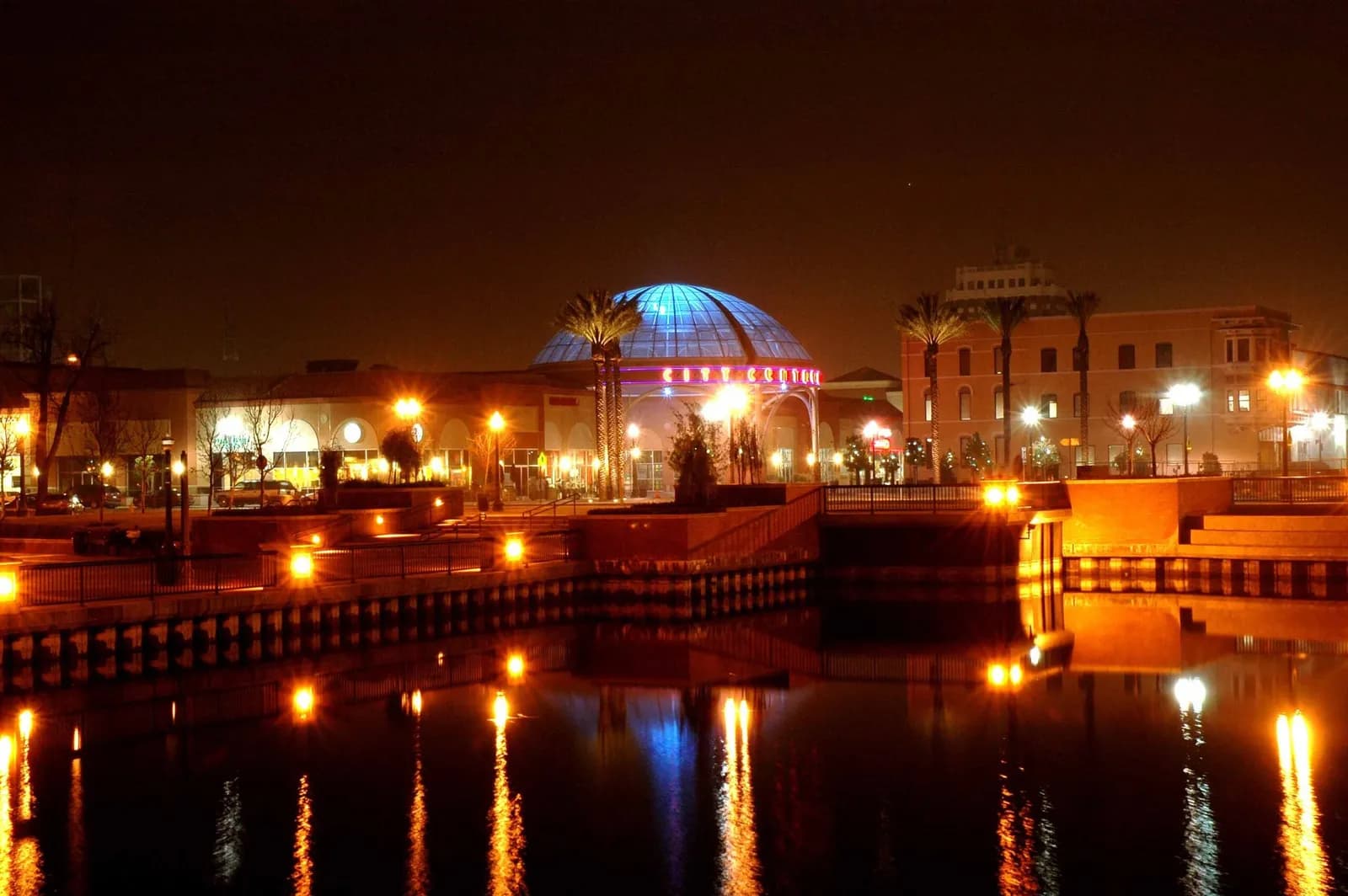 Stockton waterfront at night, with palm trees and the illuminated City Centre reflected in the water