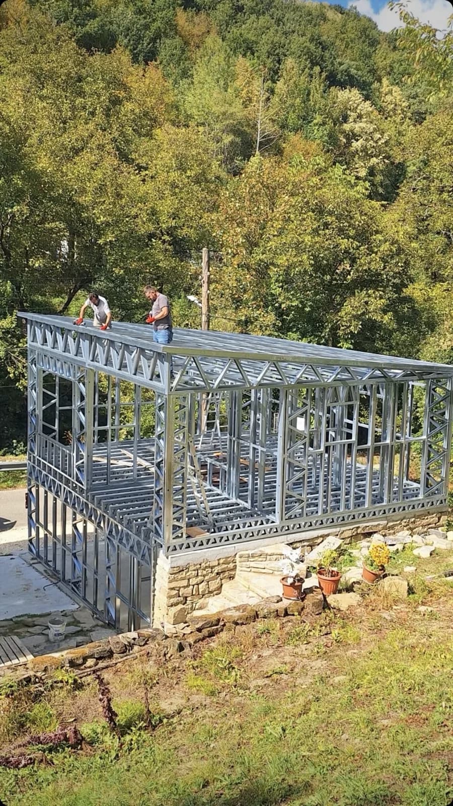 Steel framing for a residential build in progress, with two workers assembling the upper floor frame